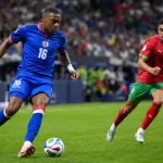 Lenny Joseph in blauw tenue tijdens een interland op een voetbalveld.