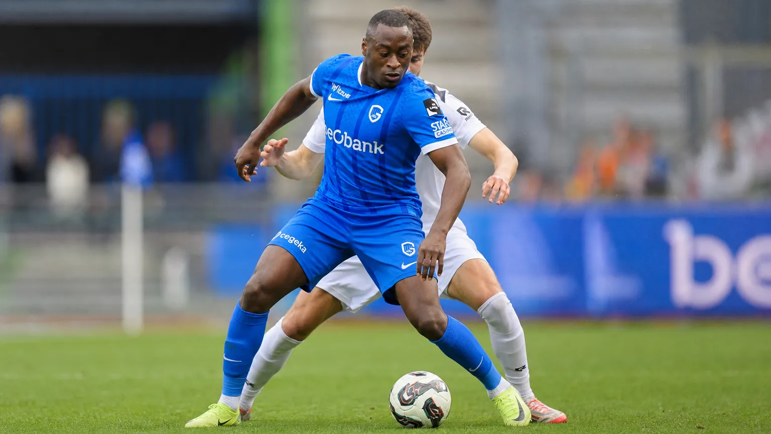 Mujaid Sadick controleert de bal in een blauw wedstrijdtenue.