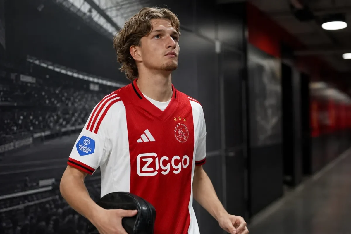Mika Godts in Ajax-tenue tijdens een wandeling door een stadionganger.