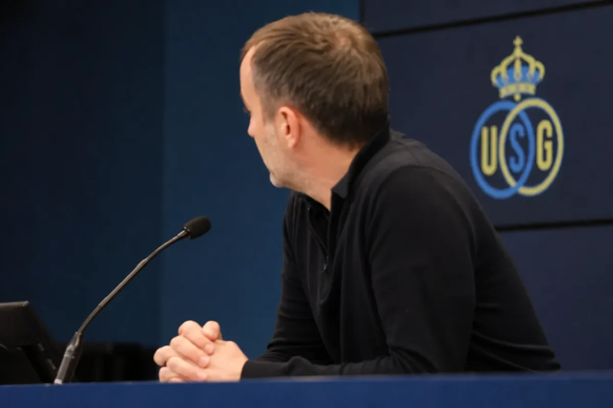 Een niet-herkenbare coach spreekt in een persruimte met een discreet Union-logo op de achtergrond.