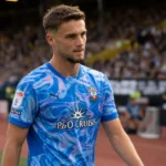 Taylor Harwood-Bellis loopt langs de zijlijn van een voetbalveld.