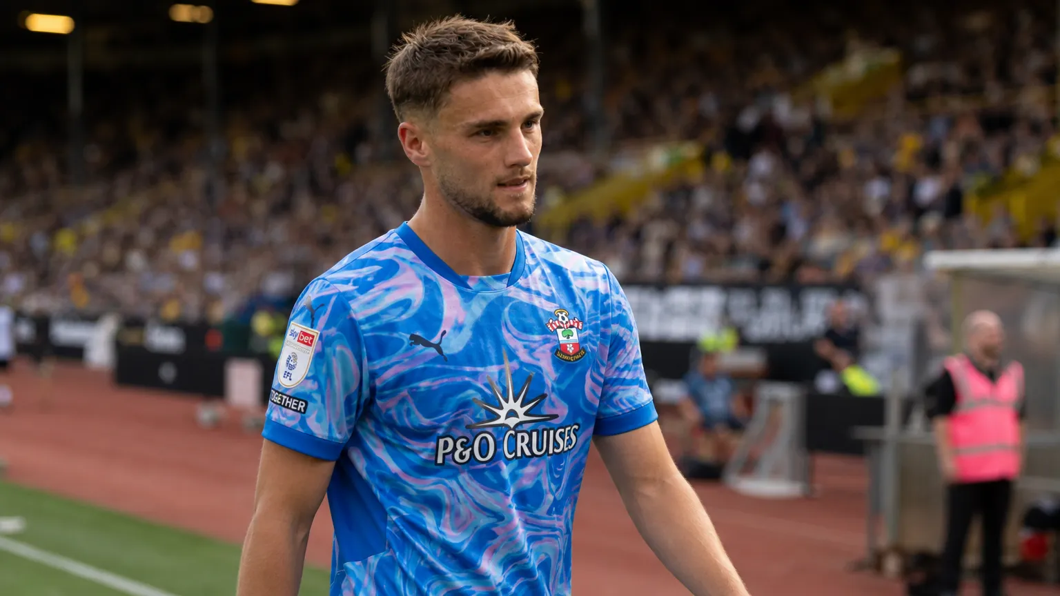 Taylor Harwood-Bellis loopt langs de zijlijn van een voetbalveld.
