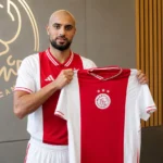 Sofyan Amrabat toont een Ajax-shirt tijdens een officiële clubpresentatie.