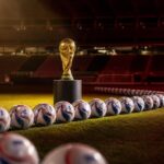 WK-trofee tussen een overvloed aan ballen in een gespannen, leeg stadion