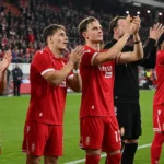 Een groep spelers van Standard Luik applaudisseert langs het veld.