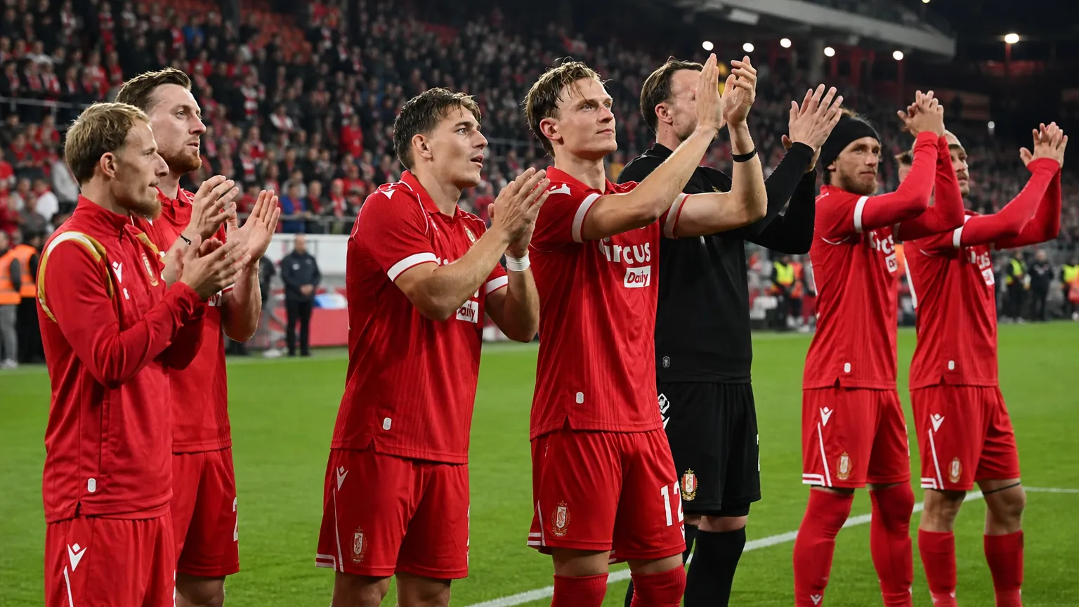 Een groep spelers van Standard Luik applaudisseert langs het veld.