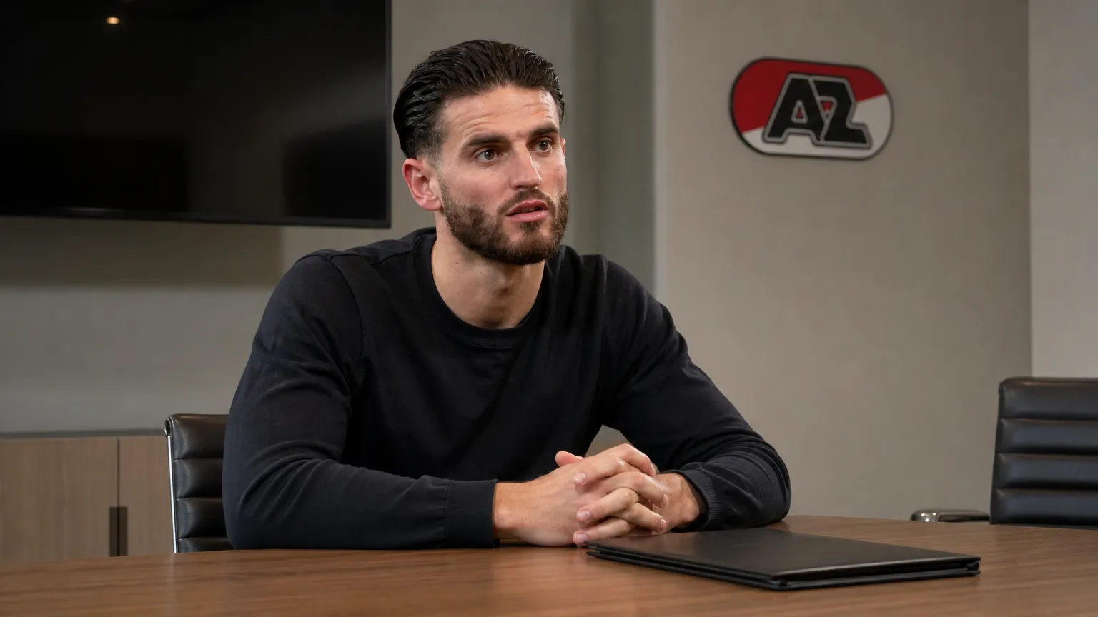 Wesley Hoedt zit in neutrale kleding in een rustige vergaderruimte met een discreet AZ-wanddetail.