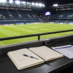 Lege persplaats in een voetbalstadion met zicht op het verlichte veld.