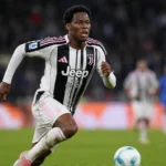 Jonathan David in een zwart-wit gestreept tenue tijdens een voetbalwedstrijd.