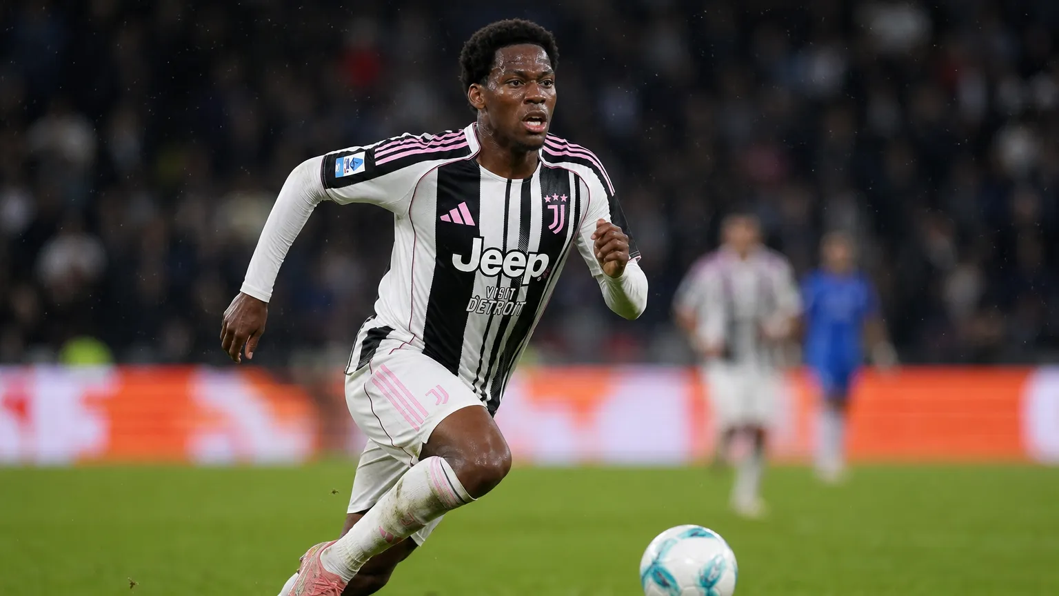 Jonathan David in een zwart-wit gestreept tenue tijdens een voetbalwedstrijd.