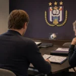 Niet-identificeerbare clubmedewerkers bespreken dossiers aan een tafel in een kantoor van Anderlecht.
