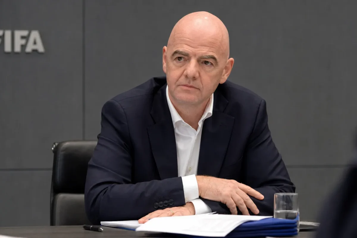 Gianni Infantino zit aan een vergadertafel in een FIFA-conferentieruimte.