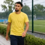 Adem Zorgane wandelt in neutrale sportkleding langs een voetbalcomplex.