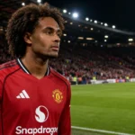 Joshua Zirkzee in het tenue van Manchester United aan de rand van het veld.
