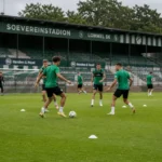 Niet-herkenbare Lommel SK-spelers trainen samen op het veld van het Soevereinstadion.