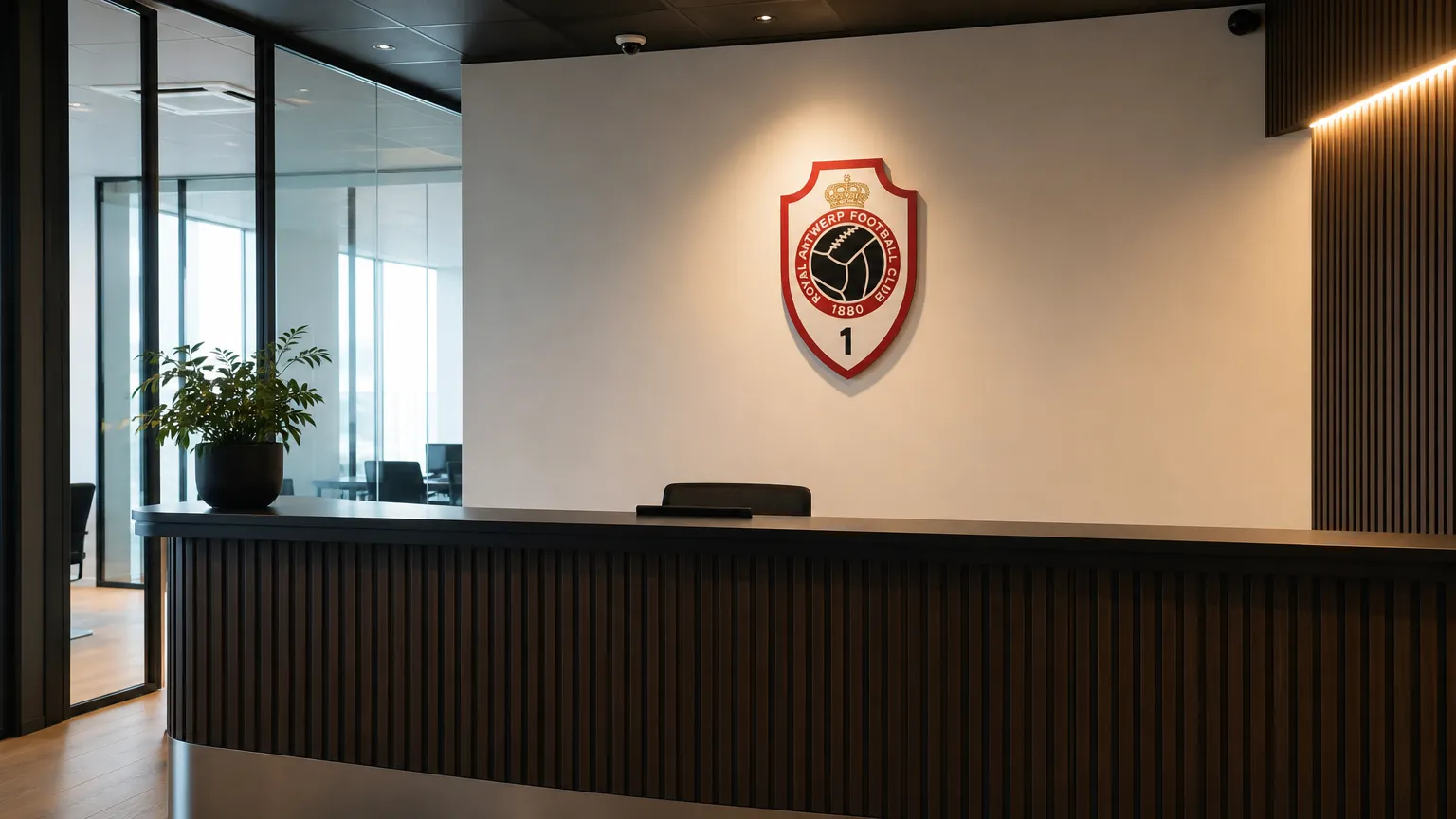 Een rustige ontvangstruimte van Royal Antwerp FC met een clublogo aan de wand.