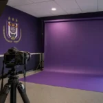 Voorbereiding van een U23-fotoshoot bij RSC Anderlecht met paarse clubachtergrond.