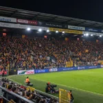 Breed beeld van een wedstrijdavond in het stadion van KV Mechelen met supporters op de tribunes.