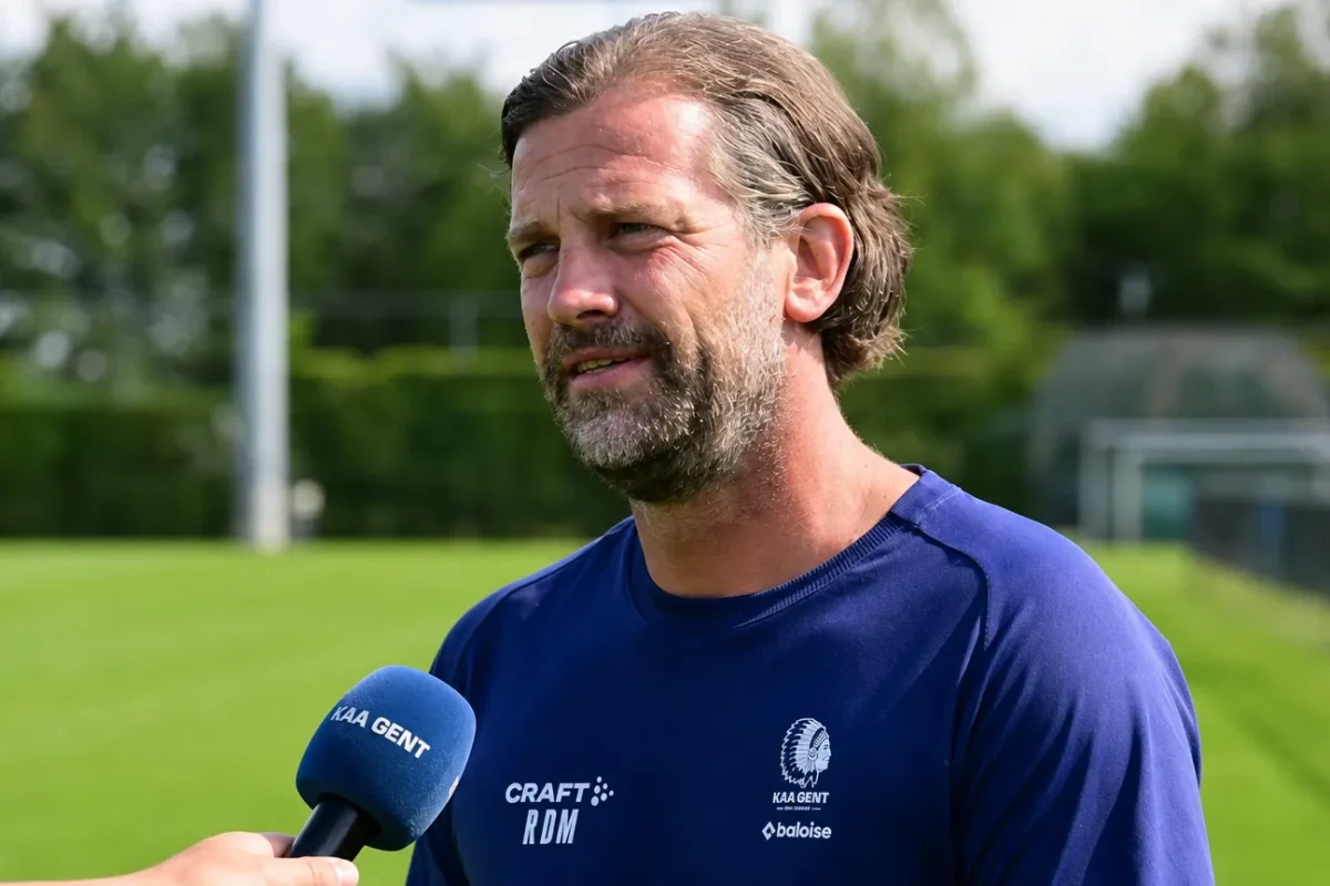 Rik De Mil spreekt in een interviewzone naast een voetbalveld.