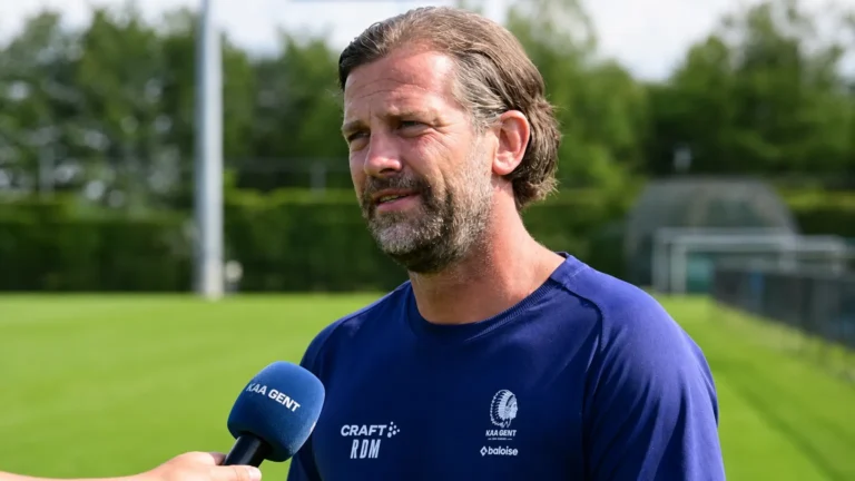 Rik De Mil spreekt in een interviewzone naast een voetbalveld.