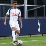Cristian Romero in het tenue van Tottenham Hotspur aan de rand van een voetbalveld.