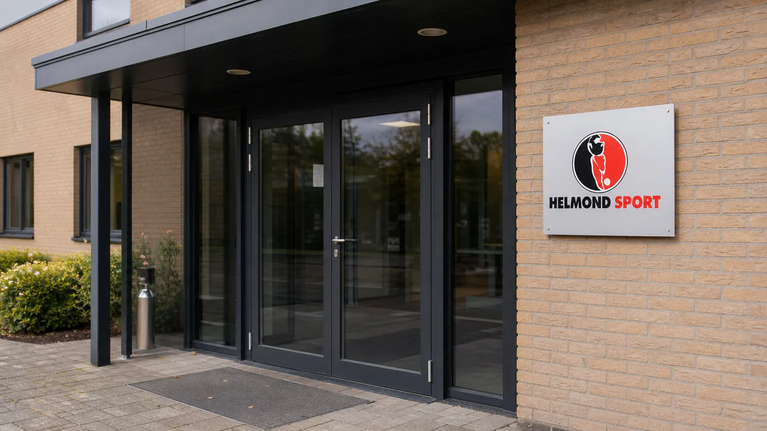 De ingang van Helmond Sport met een discreet clubbord aan het gebouw.