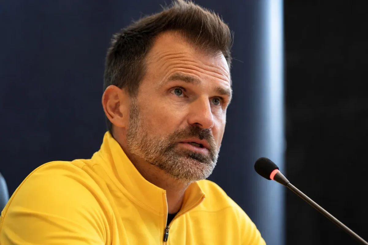 Ivan Leko spreekt op een persconferentie van Club Brugge in een gele coachtrui.