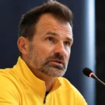 Ivan Leko spreekt op een persconferentie van Club Brugge in een gele coachtrui.