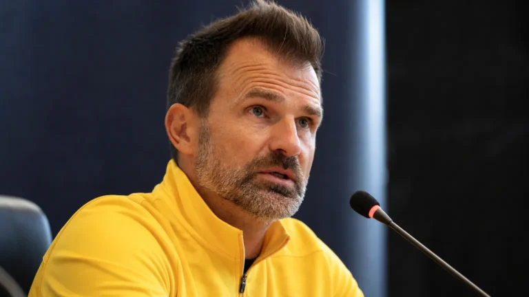 Ivan Leko spreekt op een persconferentie van Club Brugge in een gele coachtrui.