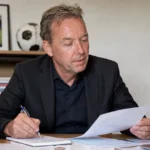 Valentijn Driessen zit aan een bureau terwijl hij notities voor een voetbalcolumn doorneemt.
