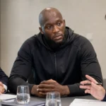 Romelu Lukaku in neutrale sportkleding tijdens een overleg aan tafel.