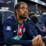 Bradley Barcola zit in tenue op de bank naast het voetbalveld.