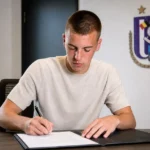 Noa Ojea ondertekent zijn nieuwe contract in een kantoor van RSC Anderlecht.