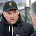 Fred Vanderbiest spreekt met een journalist aan de rand van een stadion.