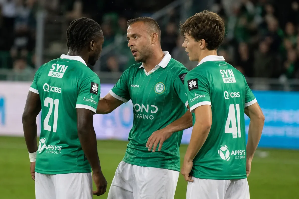Drie spelers van Lommel in groene shirts overleggen tijdens de wedstrijd.