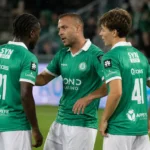Drie spelers van Lommel in groene shirts overleggen tijdens de wedstrijd.