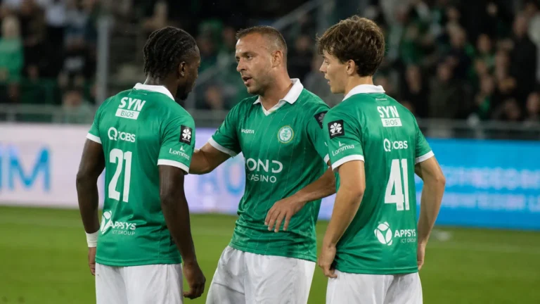 Drie spelers van Lommel in groene shirts overleggen tijdens de wedstrijd.