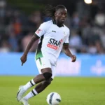 Davis Opoku in wit wedstrijdtenue tijdens een voetbalmoment op het veld.