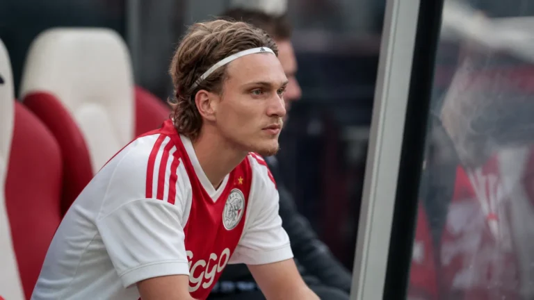 Mika Godts zit op de reservebank in zijn wit-rode Ajax-tenue.
