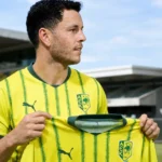 Kerim Mrabti poseert met het shirt van AEK Larnaca tijdens zijn officiële voorstelling.