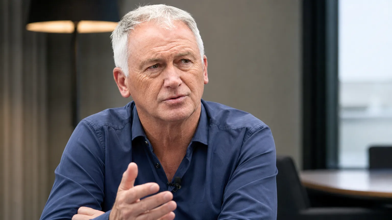 Marc Degryse tijdens een sportjournalistiek interview in een rustige studioruimte.