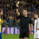 Een scheidsrechter toont tijdens een voetbalwedstrijd een gele kaart.