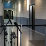 Een lege mixed zone met microfoons en opnameapparatuur na een voetbalwedstrijd.
