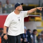 Tim Bakens geeft aanwijzingen langs de zijlijn tijdens een voetbalwedstrijd.