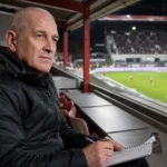 Patrick Goots in zwarte jas op de perstribune van de Bosuil.