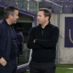 Neutrale medewerkers in de technische zone van een stadion met een discreet Anderlecht-bord op de achtergrond.