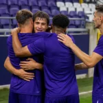 Een groep Anderlecht-spelers viert samen op het veld na de wedstrijd.