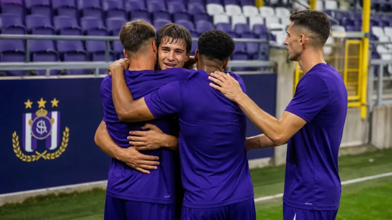 Een groep Anderlecht-spelers viert samen op het veld na de wedstrijd.