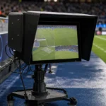 Een ingeschakeld VAR-scherm langs de zijlijn van een voetbalveld.