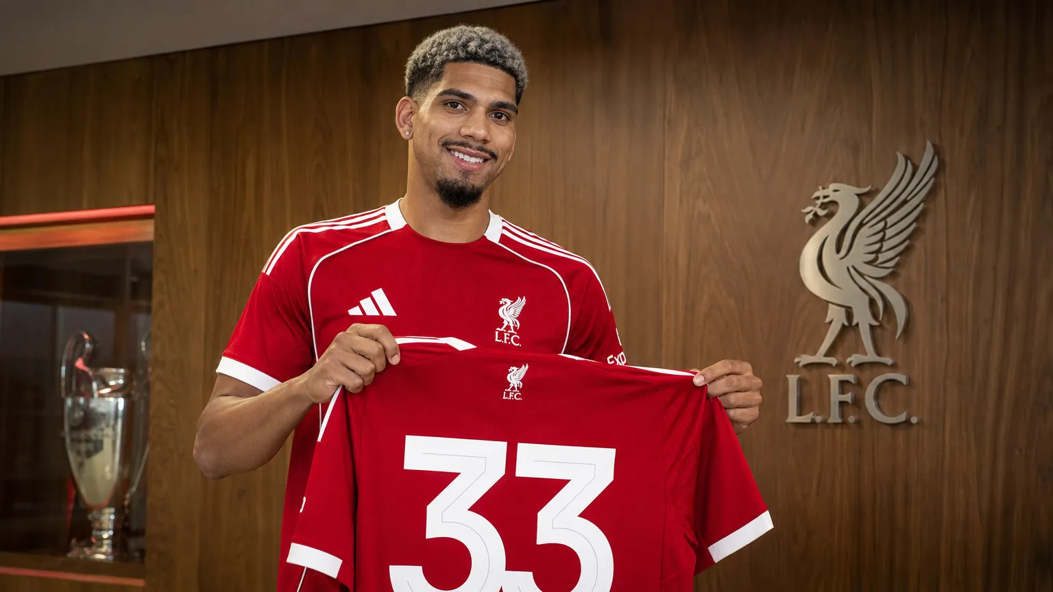 Ronald Araújo houdt tijdens zijn officiële voorstelling een Liverpool-shirt met rugnummer 33 vast.